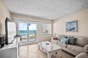 a living room with a couch and a table and a tv at Holiday Surf and Racquet Unit 520 in Destin