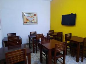a dining room with tables and a tv on a wall at Hotel Natal in Santos