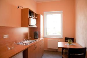 eine Küche mit einem Waschbecken, einem Tisch und einem Fenster in der Unterkunft Apartmenthaus Wesertor in Kassel