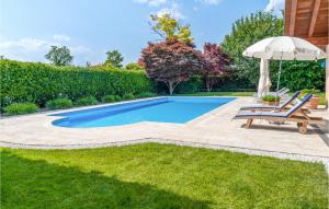 a swimming pool with an umbrella and two chairs and an umbrella at 5 Bedroom Cozy Home In Fanzolo Di Vedelago in Fonzolo