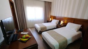 um quarto de hotel com duas camas e uma mesa com uma tigela de fruta em Christmas Hotel - Jerusalem em Jerusalém