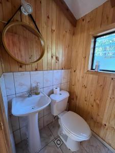 Łazienka z białą toaletą i umywalką w obiekcie Cabañas Bosque las Trancas w mieście Las Trancas