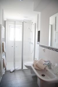 ein weißes Bad mit einer Dusche und einem Waschbecken in der Unterkunft Apartmenthaus Wesertor in Kassel