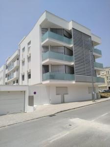 a white apartment building with balconies on a street at Apartamento Estrela do Mar in Nazaré +16 photos