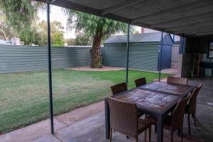 un tavolo e sedie in legno su un patio con un albero di 4 Bedrooms, 2 Bathrooms in Alice Springs a Alice Springs