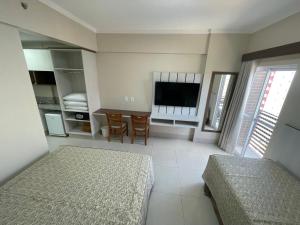 a bedroom with a bed and a tv and a table at Spazzio diRoma com acesso ao Acqua Park, Splash e Slide in Caldas Novas