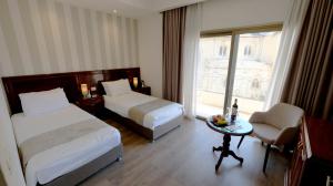 um quarto de hotel com duas camas e uma mesa e uma janela em Christmas Hotel - Jerusalem em Jerusalém