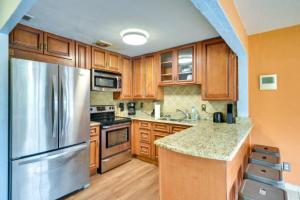 a kitchen with wooden cabinets and a stainless steel refrigerator at Florida Escape with Pool, Near Beaches and Kayaking! in Daytona Beach