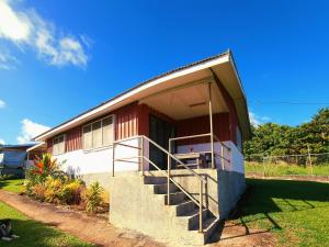 Casa roja y blanca con porche y escaleras en Eua Accommodation en ‘Ohonua