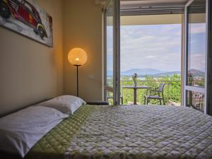 アローナにあるCasa Ierardi - Appartamento Arona Bellavistaのベッドルーム1室(ベッド1台付)、景色を望むバルコニーが備わります。