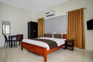 1 dormitorio con 1 cama grande y 1 mesa en Collection O Lux villa en Nedumbassery