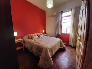 a bedroom with a bed and a red wall at CasaOma in Río Cuarto