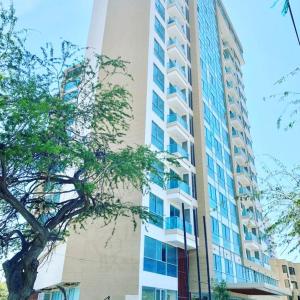 a tall building with a tree in front of it at Apartasuite moderno y elegante en Playa Salguero in Gaira