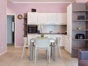 アローナにあるCasa Ierardi - Appartamento Aronaの白いキャビネット、テーブルと椅子付きのキッチンが備わります。