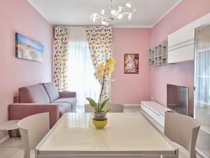 アローナにあるCasa Ierardi - Appartamento Aronaのピンクの壁のリビングルーム(白いテーブル付)