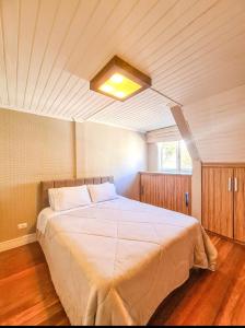 - une chambre avec un grand lit blanc et un plafond dans l'établissement Condomínio fechado a 11 minutos a pé do Centrinho, à Campos do Jordão