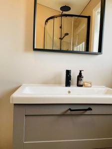ein Badezimmer mit einem weißen Waschbecken und einem Spiegel in der Unterkunft Stylish cottage with hot tub in Stóri-Ás