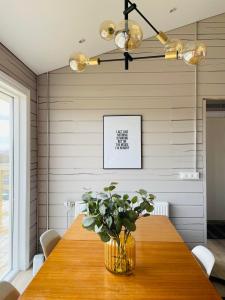 a dining room with a wooden table and a vase with a plant at Stylish cottage with hot tub in Stóri-Ás