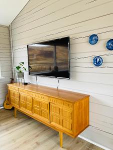 a television on a wall with a wooden cabinet at Stylish cottage with hot tub in Stóri-Ás