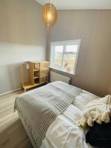 a bedroom with a large bed with a window at Stylish cottage with hot tub in Stóri-Ás