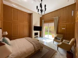 um quarto com uma cama, uma cadeira e um lustre em Villa de luxe L'MNAM em Marrakech