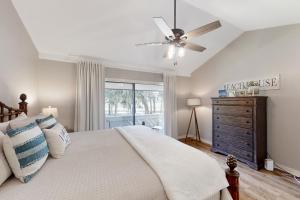 费南迪纳比奇Sea Marsh Retreat Condo in Fernandina Beach in a gated community的一间卧室配有一张带吊扇和梳妆台的床。