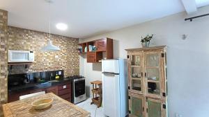 a kitchen with a white refrigerator and a table at Apartamento na Praia do Amor-Pipa in Pipa