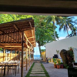 um pátio com uma mesa e cadeiras e o oceano em Mabuhay Dauin Dorm Hostel em Dauin