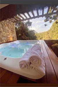 a bath tub with towels sitting on top of it at Chalét-Casa e Bangalo- Villa-Jacuzzi-Sauna-Lareira-Privativo in Campos do Jordão