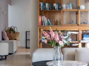 een vaas met roze bloemen op een tafel in een woonkamer bij Charming villa with indoor swimming pool within walking distance from beach and town centre in Koksijde
