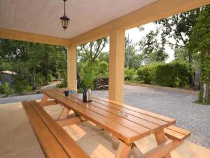 een houten picknicktafel op een patio bij Alluring Holiday Home in Largenti re with Pool in Largentière