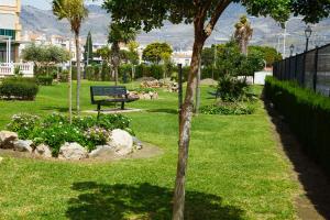a park with a bench and flowers in the grass at Tranquilidad y playa para toda la familia in Calahonda