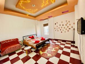 a room with a bed and a tv and a checkered floor at Dnut's House in Hanoi
