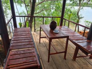 un gato sentado en una mesa de madera en un porche en Nam Binh Homestay, en Ben Tre