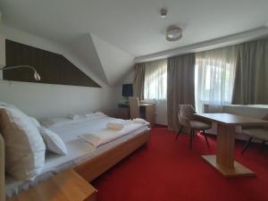 a hotel room with a large bed and a table at Corvina Hotel-Restaurant in Mosonmagyaróvár