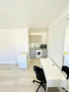 a white kitchen with a white desk and chairs at Green Lanes in London
