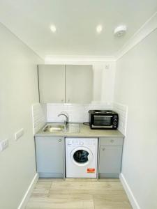 a kitchen with a washing machine and a microwave at Green Lanes in London