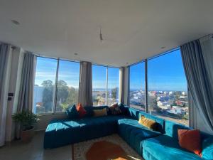 a large blue couch in a room with large windows at Appartement 1 chambre spacieuse vue panoramique in Tangier