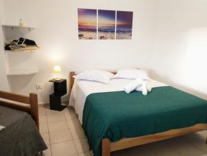 a bedroom with a bed with a green blanket at Recanto da Lagoa Flat in Ilha Comprida