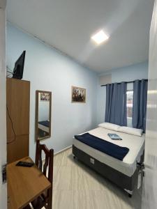 - une chambre avec un lit, une table et un miroir dans l'établissement Hotel Cidade Paisagem, à Piquete