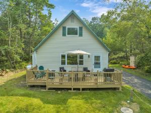 a house with a deck with chairs and an umbrella at The Sage Chalet in Emerald Lakes, Poconos! in Long Pond