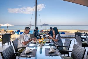 a group of people sitting at a table on the beach at Aleenta Resort And Spa, Phuket-Phangnga - SHA Plus in Natai Beach
