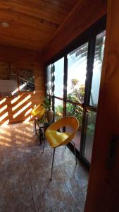 Habitación con 2 sillas y ventanas amarillas. en Viví Iguazú Casa Familiar en Puerto Iguazú