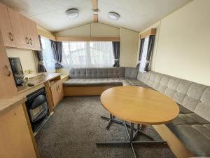 uma pequena sala de estar com uma mesa e um sofá em Lovely Caravan At Valley Farm Holiday Park, Sleeps 8 Ref 46127v em Great Clacton