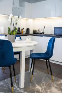 uma cozinha com uma mesa branca e 2 cadeiras azuis em Baltic Gdansk OLD TOWN em Gdansk