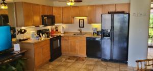 a kitchen with wooden cabinets and a stainless steel refrigerator at Kihei Kai Nani Resort in Kihei