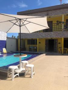 a large white umbrella sitting next to a swimming pool at Paraíso dos Oliveira in São José da Coroa Grande