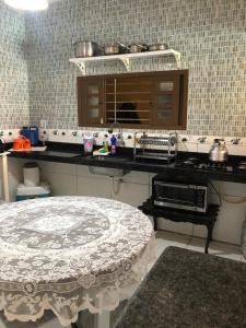 a kitchen with a table and a counter with pots and pans at Paraíso dos Oliveira in São José da Coroa Grande