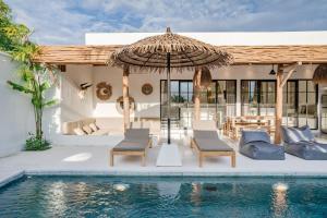 eine Terrasse mit Stühlen und einem Sonnenschirm neben einem Pool in der Unterkunft Villa Ruta I - Sumptuous 2BR Private Luxury Villa Walking Distance to Nyanyi Beach in Tanah Lot