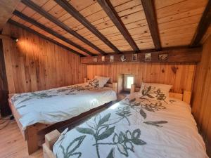Dos camas en una habitación con paredes de madera. en Gîte familial dans le massif du Pilat avec confort inclus - FR-1-496-294, en Doizieux